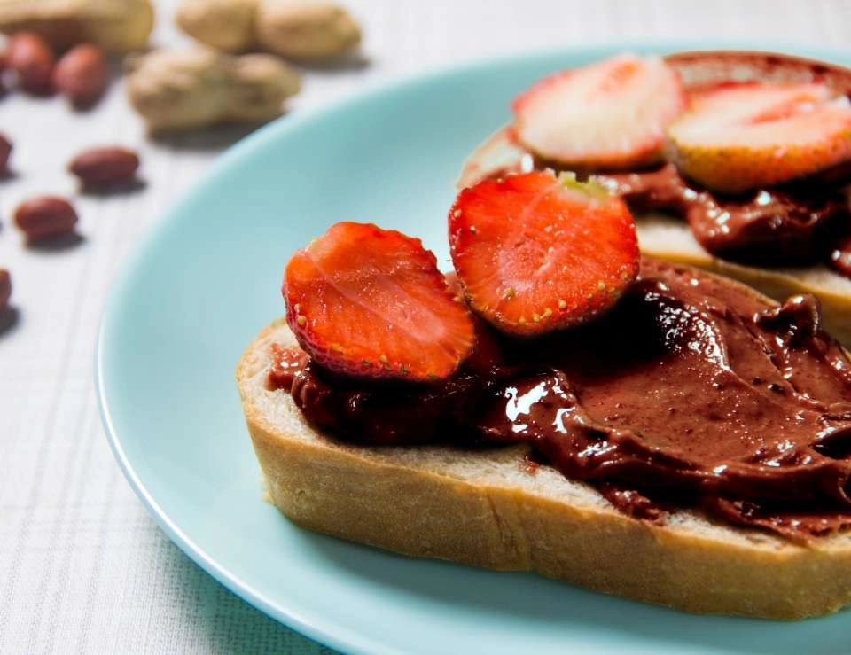 Pasta de amendoim sabor chocolate com morango em uma fatia de pão de forma