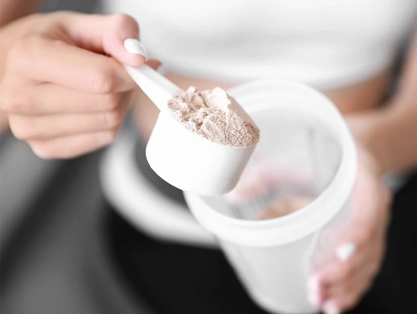 A mão de uma pessoa com um scoop de Creatina Creapure 100g